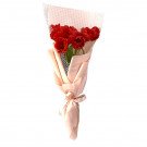 Bouquet of red tulips wrapped in pink paper and white mesh, tied with a pink ribbon.
