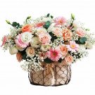 Flower arrangement in a basket with pink and white roses, gerbera daisies, and baby's breath.