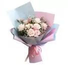Bouquet of pink and white roses and carnations with baby's breath, wrapped in light blue and pink paper.