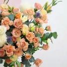 A large bouquet of peach roses, white chrysanthemums, and purple thistle.