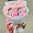 A bouquet of pink carnations and small white flowers, wrapped in paper with Hello Kitty designs.