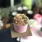Chocolate cupcake with swirled frosting, slivered almonds, and a pink polka dot wrapper.