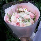 A bouquet of pale pink and white flowers, including roses, carnations, and gerbera daisies.