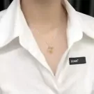 Silver heart-shaped pendant necklace with light brown stone on a white collared shirt.