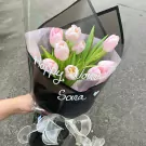 Pink tulips in a black wrapper with "Happy Women's Day Sara" written in white.