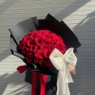 Bouquet of 50 red roses with a large ivory bow and red ribbon accents.