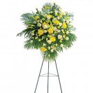 Funeral flower stand with yellow lilies, chrysanthemums, and roses.