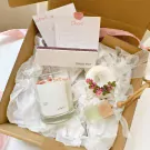 Scented candle gift set with dried flowers and decorative cards in a box.