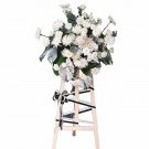 White funeral flower arrangement with roses and chrysanthemums on a wooden easel.