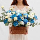 Basket of blue and white flowers including chrysanthemums, roses, and carnations.