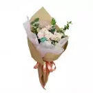Bouquet of pale pink roses, daisies, and greenery wrapped in brown paper and tied with ribbon.
