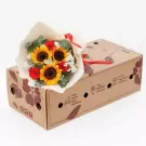 Bouquet of sunflowers and red roses on a cardboard box.