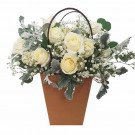 Basket of white roses and baby's breath in a brown pot.
