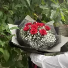 Bouquet of 9 red roses and baby's breath, wrapped in black and white paper.