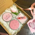 Pink gift box with scented candles, a tulip, and a hair clip.
