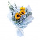 Bouquet of sunflowers and blue hydrangeas in light blue wrapping with a white ribbon.