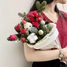 Christmas bouquet with red roses, pine, ornaments, and a Santa snowman figure.