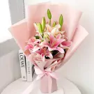 Pink lilies wrapped in pale pink paper with a pink ribbon.