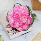 Pink carnation bridal bouquet on a book.