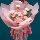 Pink rose, hydrangea, and carnation bouquet in pastel colors, wrapped in pink paper.