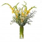 Yellow gladiolus and other flowers in a clear glass vase.