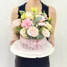 Pink floral arrangement on a money cake box, held by a person.