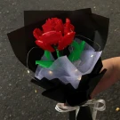 Red Lego rose bouquet with green leaves, black and white wrapping paper, and fairy lights.