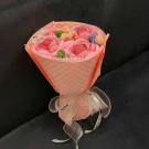 Knitted pink rose bouquet with colorful accents and a ribbon bow, wrapped in pink paper.