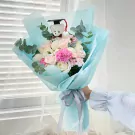 Graduation bouquet with a teddy bear in a cap, pink and white roses, carnations, and eucalyptus.