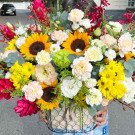 A basket of sunflowers, carnations, roses, and other flowers.