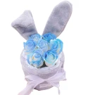 Woman holding pink gift bags with floral bouquets inside, one bag is transparent with a bow.