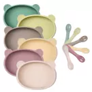 Stack of bear-shaped silicone plates in pastel colors with matching spoons.