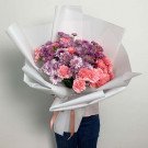 Large bouquet of pink carnations and purple chrysanthemums wrapped in white paper.