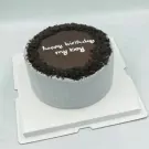 A round grey cake with chocolate ganache and cookie crumbs, reading "happy birthday my boy".