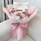 Subtle pink bouquet of roses and other flowers, wrapped in pink paper and tied with a ribbon.