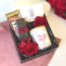 Valentine's gift box with a chocolate bar, scented candle, and red roses.