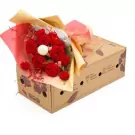 Red roses and carnations in a bouquet on a cardboard box.
