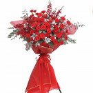 Grand bouquet of red roses and red orchid sprigs on a stand with red fabric.