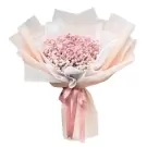Pink baby's breath bouquet wrapped in sheer paper with a pink ribbon.