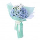 Blue hydrangeas and white daisies in a light green bouquet wrap, tied with a white ribbon.