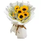 Bouquet of sunflowers and purple statice flowers, wrapped in white paper and tied with a brown ribbon.