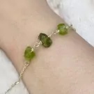 Silver bracelet with raw green peridot stones on a wrist.