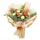A bouquet of orange and yellow carnations with baby's breath, wrapped in beige paper and tied with a ribbon.