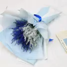 Bouquet of blue and silver artificial flowers wrapped in light blue paper with a blue ribbon.