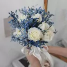 White roses and blue flowers with a white ribbon.
