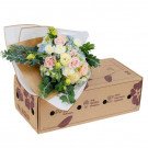 A bouquet of pastel roses, carnations, lisianthus, and hydrangeas in a gift box.