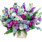 Purple and pink flowers in a wooden box with a pink ribbon.