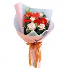Bouquet of pink roses and orange gerberas with green leaves, wrapped in pink and blue paper with a ribbon.