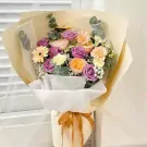 Bouquet of purple roses, orange roses, yellow gerberas, and white carnations.
