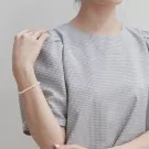 Close-up of a person's arm wearing the Azure Pearl Bracelet on a light background.